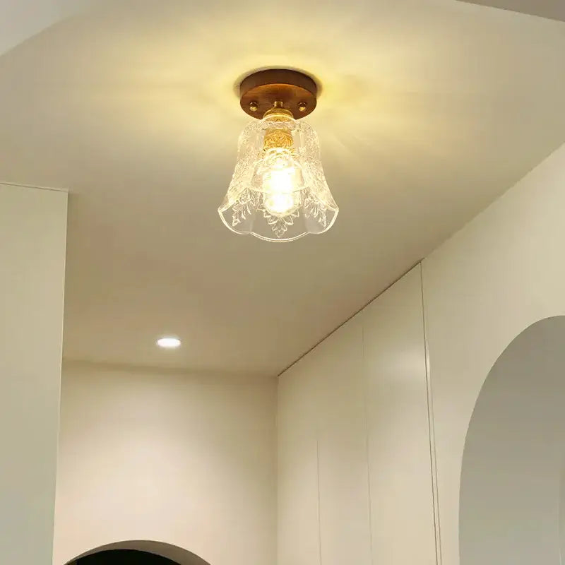 A warm-toned glass led ceiling lamp with brass base and floral etched shade for living room use