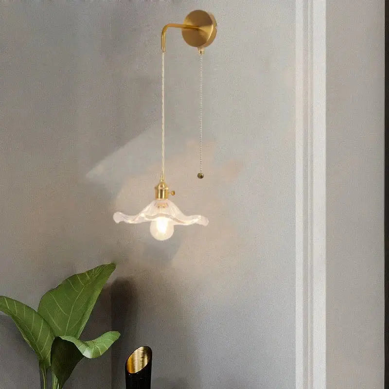 A delicate white floral glass copper led wall sconce with gold finish and pull chain for bathroom lighting