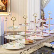 Gold-finished tiered dessert stand with white bone china fruit plates set featuring delicate pink and green floral patterns