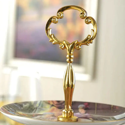 Golden ornate serving handle with intricate scrollwork on a floral gold bone china fruit plates set tiered stand