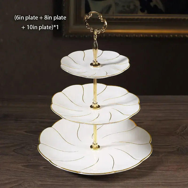 White ceramic three-tiered bone china fruit plates set with gold leaf detailing and decorative golden handle for dining room