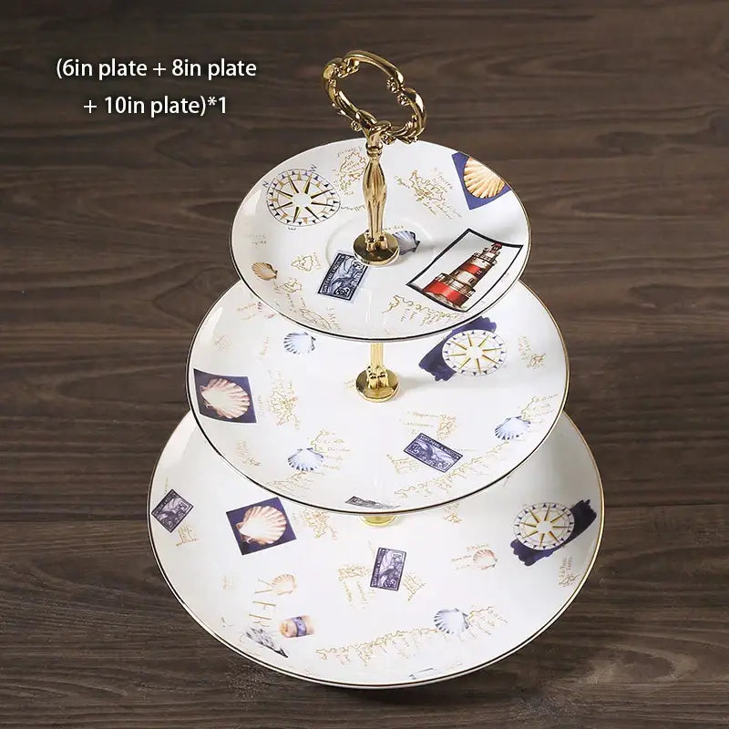 Three-tiered bone china fruit plates set with floral nautical illustrations and gold trim on an ornate gold stand