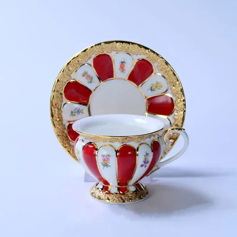 Elegant red and white porcelain tea cup with gold trim and floral motifs in a scalloped cup saucer set