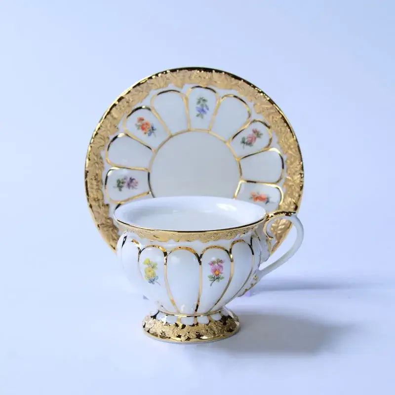 White porcelain tea cup saucer set with delicate gold trim and hand-painted floral motifs in soft pastel hues