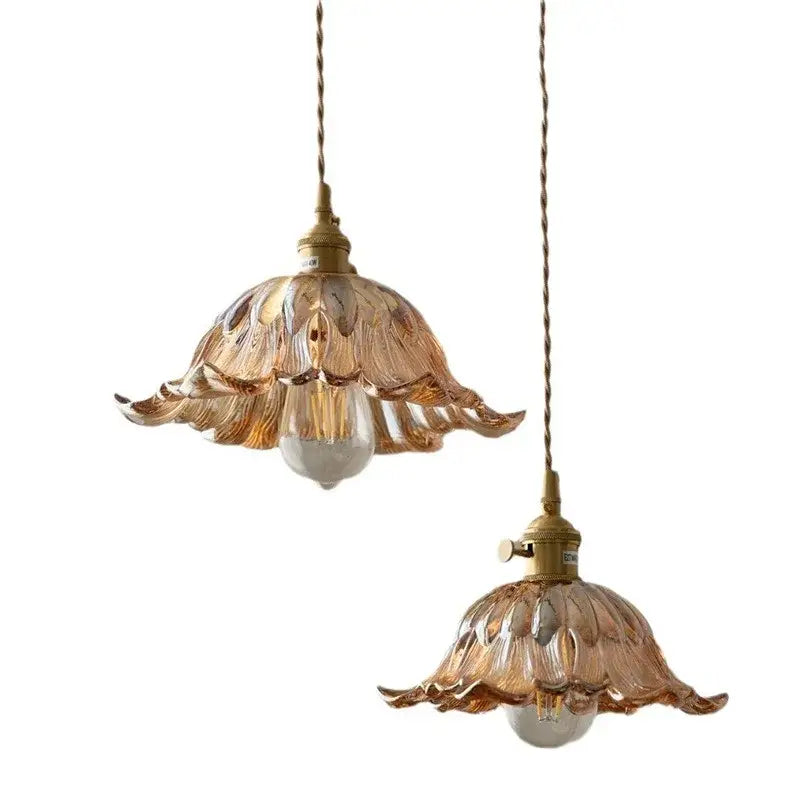 Two elegant amber glass pendant lights with gold-toned metal fixtures and twisted cords for dining room use