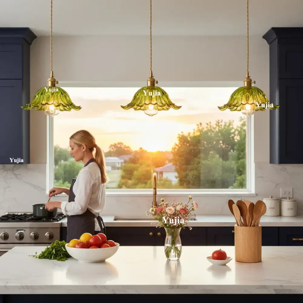 Three elegant green glass pendant lights with brass fixtures featuring green glass shades hang above kitchen island