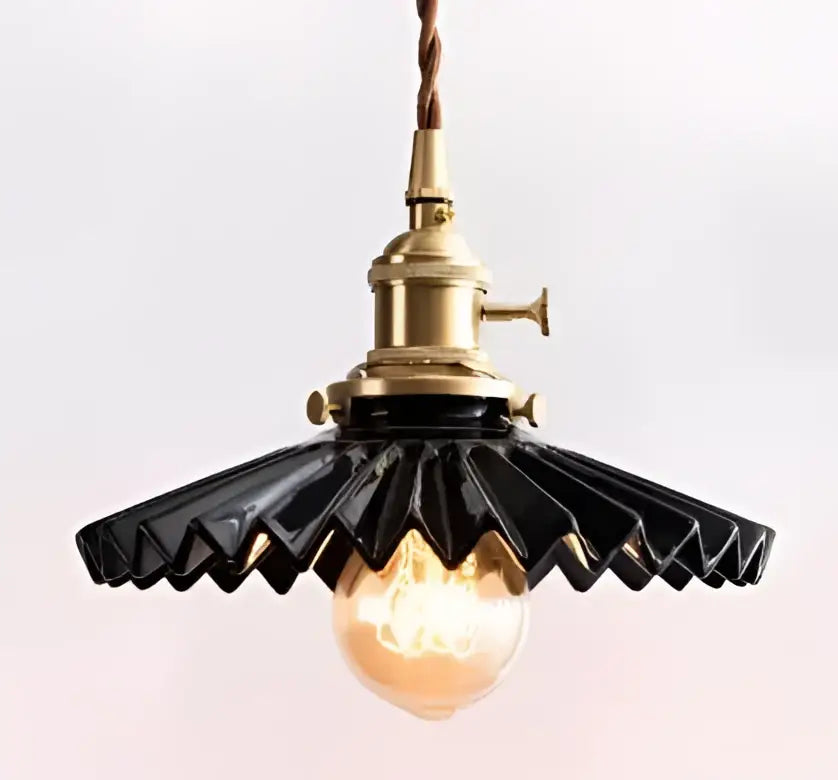 Black ceramic pendant light with brass hardware and filament bulb complements floral green glass pendant lights