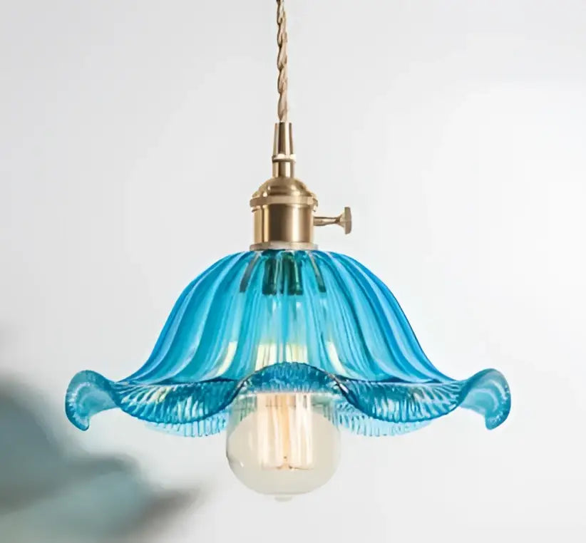 A delicate blue glass pendant light with fluted petal design and brass hardware for dining rooms