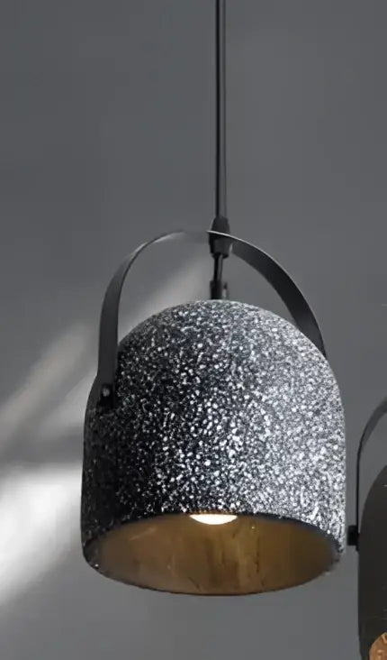 Industrial-style pendant light with speckled gray concrete exterior and warm brass interior, styled for dining room use