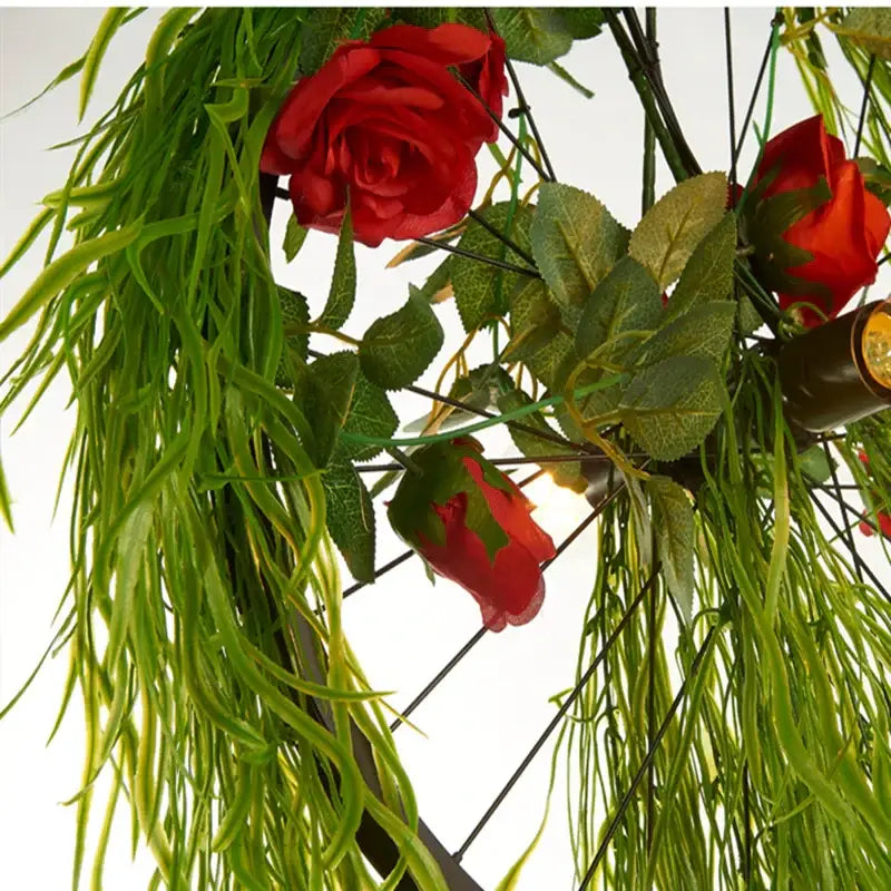A decorbites green plant lighting chandelier featuring vibrant red artificial roses and cascading weeping willow leaves for dining room decor