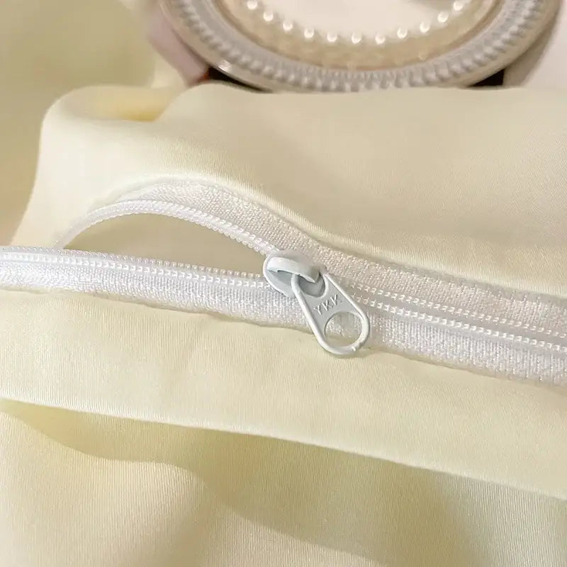 A sleek white zipper with metallic pull tab on floral ivory embroidered egyptian cotton bedding set