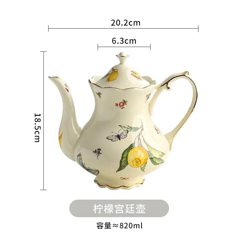 Cream-colored porcelain tea set featuring a teapot with yellow lemon and butterfly motifs and gold trim accents