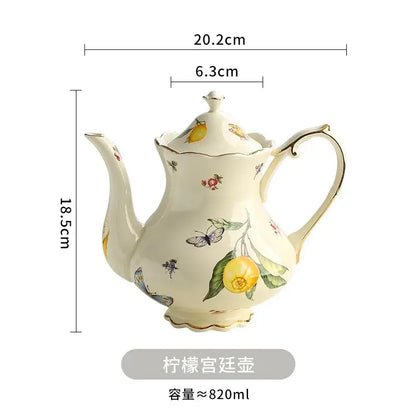 Cream-colored porcelain tea set featuring a teapot with yellow lemon and butterfly motifs and gold trim accents