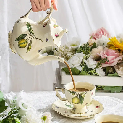 Cream-colored porcelain tea set teapot with delicate lemon floral illustrations and gold trimmed edges for dining room use