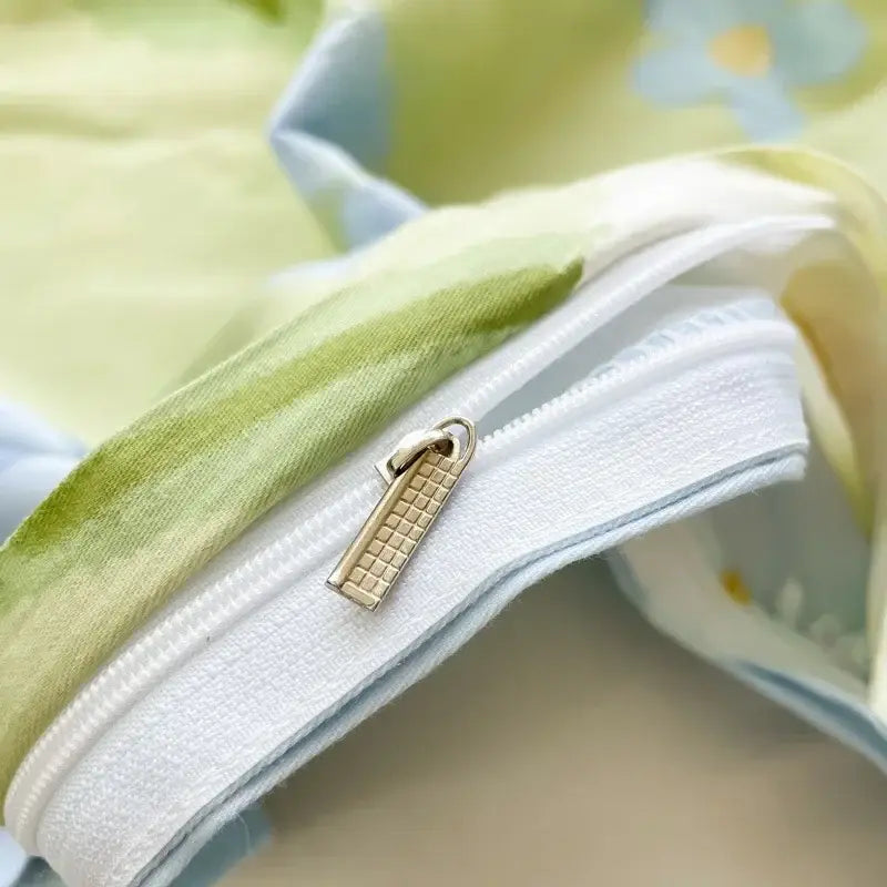 Gold-toned zipper pull with textured grid pattern on white edge of floral mint green cotton duvet cover decorbites cotton duvet