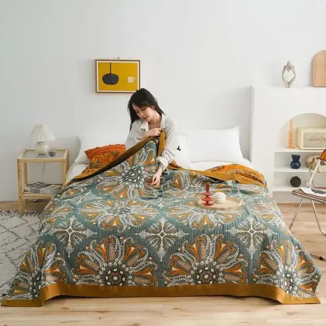 A cozy teal and gold floral cotton summer throw blanket draped on bed perfect for decorbites cotton summer decor