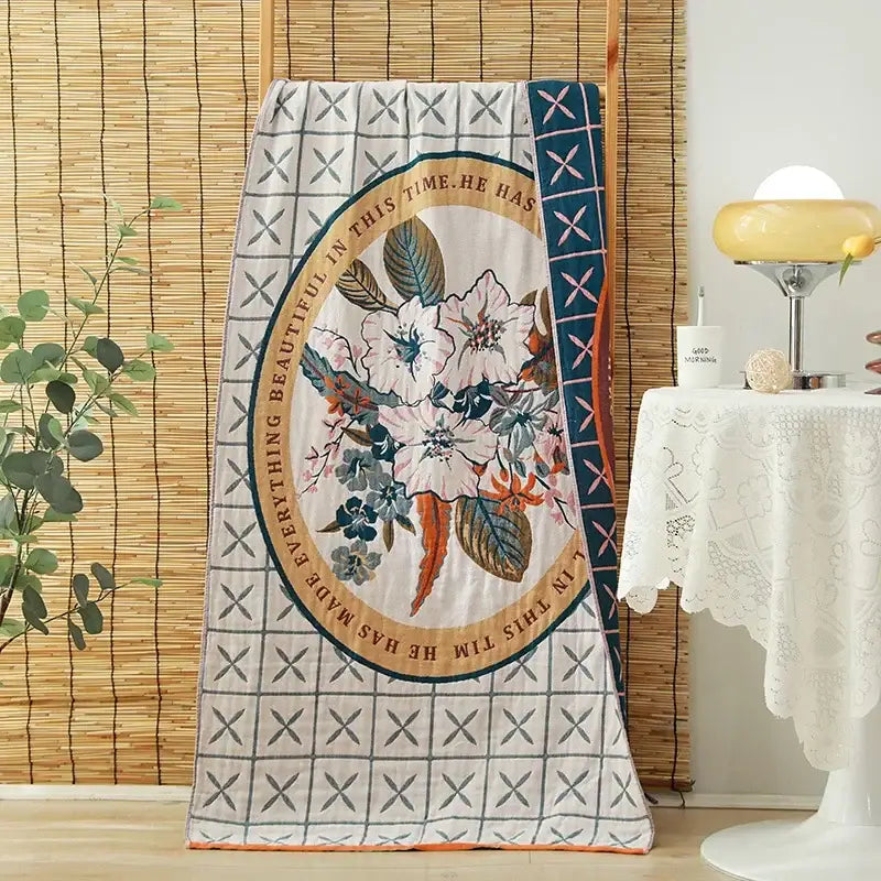 A cream-colored decorbites cotton gauze adult bath towel with floral oval design and gold trim for elegant bedroom decor