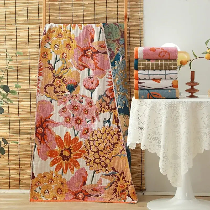 A vibrant floral orange and pink cotton gauze adult bath towel with warm tones and soft fabric texture for decorbites decor