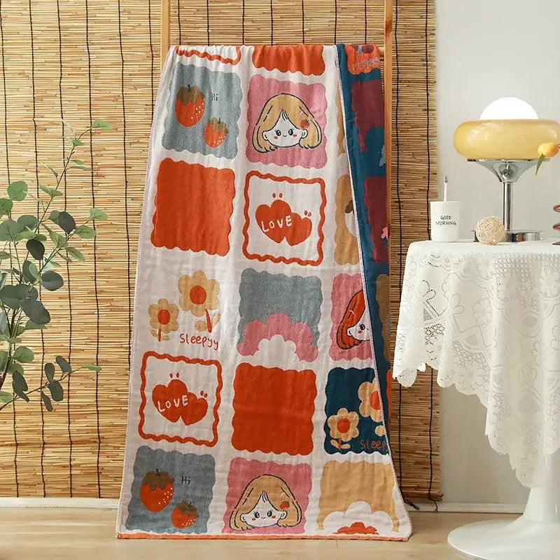A cozy floral orange and pink cotton gauze adult bath towel with playful cartoon faces and strawberries decorbites cotton gauze