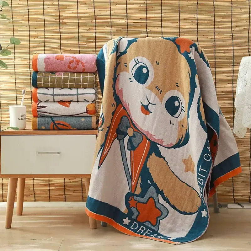 A soft beige and orange cartoon rabbit-themed bath towel with blue border and star details made of decorbites cotton gauze