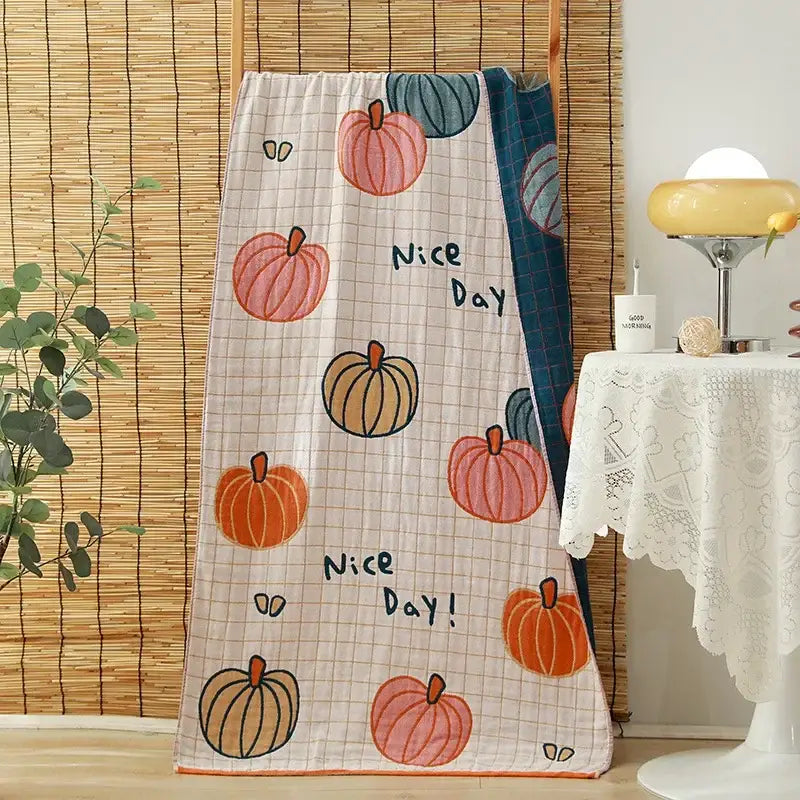 A soft light-colored cotton gauze adult quilted blanket featuring cartoon pumpkins and nice day print for decorbites bath towels decor