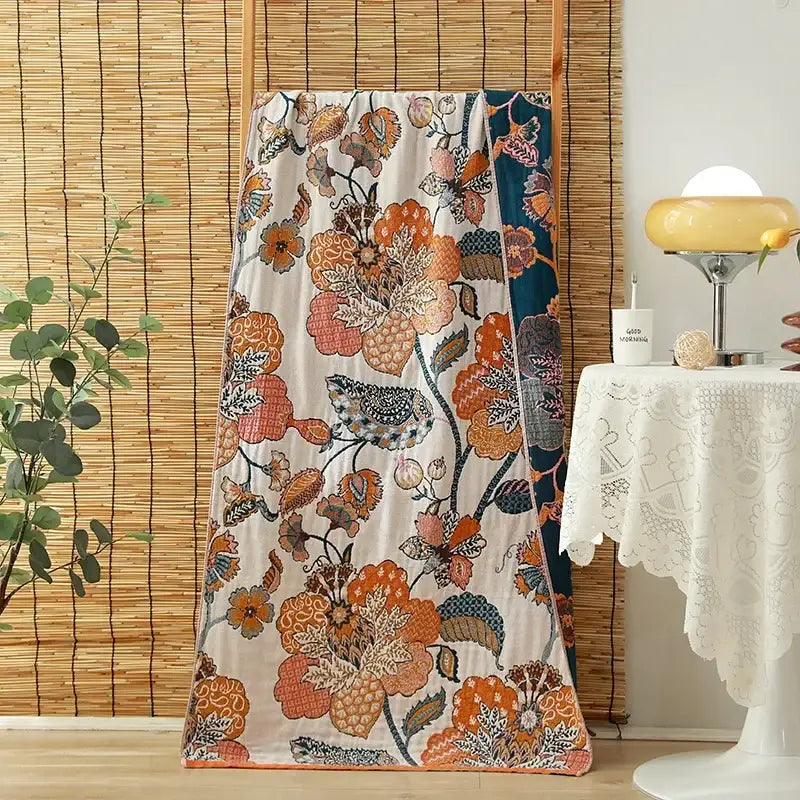 A cream-colored plush cotton gauze adult bath towel with vibrant orange and pink floral decorbites design for bedroom decor