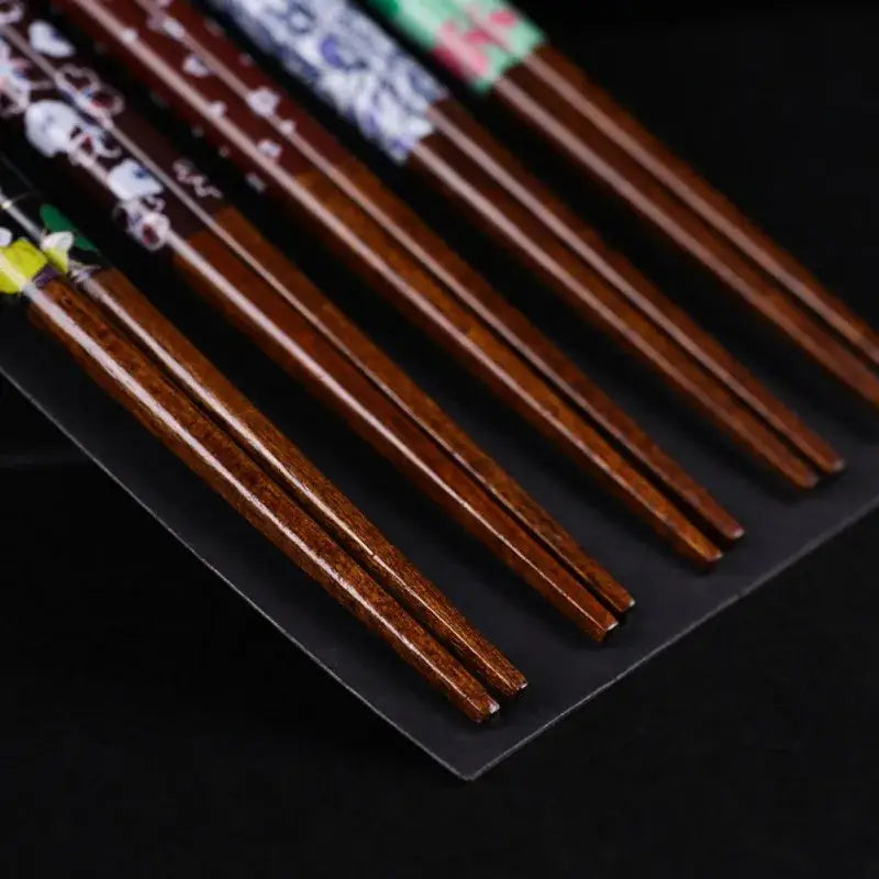 Set of brown bamboo wood chopsticks with floral and character patterns near the tips in a dining room gift box