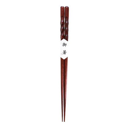 Dark brown bamboo wood chopsticks with twisted handles and a white paper band featuring japanese characters