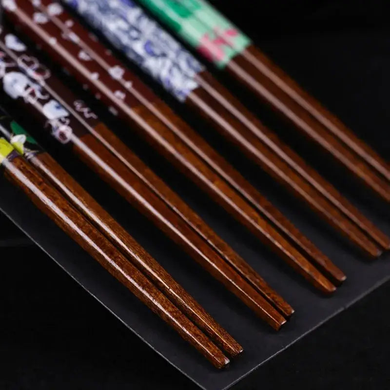 Set of bamboo wood chopsticks with floral painted handles in various colors in a dining room gift box