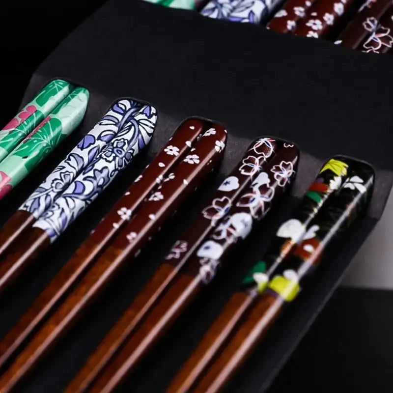 Set of bamboo wood chopsticks with glossy wooden handles and vibrant floral patterns in a dining room gift box