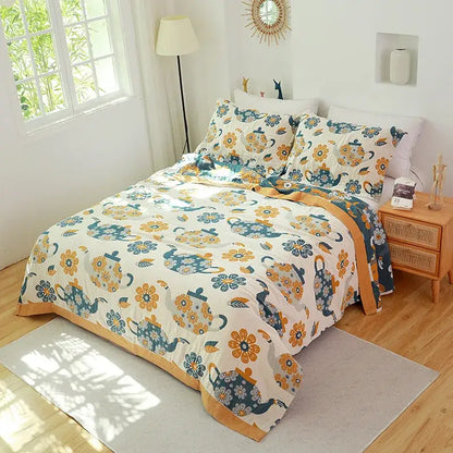 Cream-colored quilted decorbites cotton gauze towel blanket with teal and mustard-yellow teapots and floral pattern border