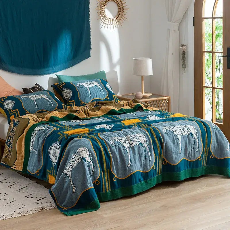 Teal and gold horse patterned quilt set with embroidered detailing paired with a floral pink and blue decorbites cotton gauze towel blanket