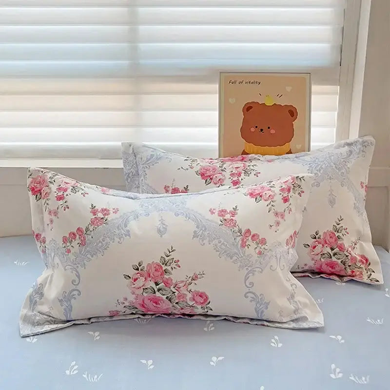 Cream-colored pillowcases with pink rose floral patterns and light blue ornate borders in decorbites cotton printed bedding set
