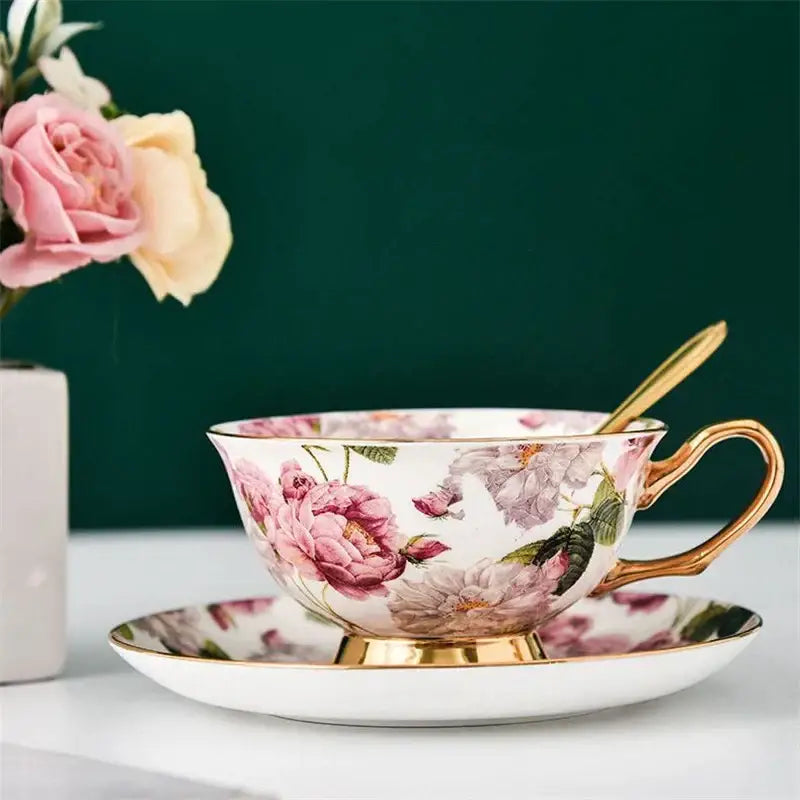Elegant floral pink and purple porcelain tea cup set with gold-trimmed rim and handle on matching saucer