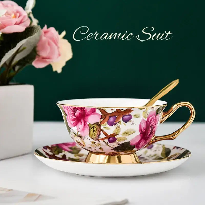 Delicate ceramic tea cup set with vibrant pink roses purple berries and gold trim on white porcelain for dining room
