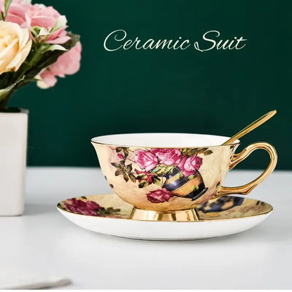 Elegant porcelain tea cup set with gold-trimmed edges and pink rose floral pattern on warm golden background
