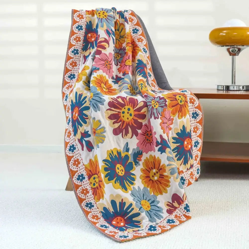 A vibrant floral-patterned bath towel in pink yellow cotton gauze with bold blossoms and lace-like border decorbites cotton gauze
