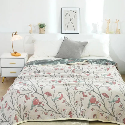 A soft cream cotton gauze summer blanket with gray branches red berries and pink and blue birds pattern