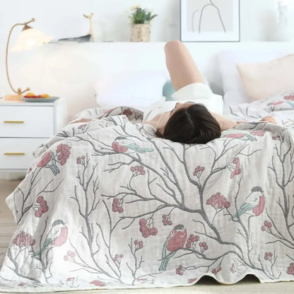 A soft off-white cotton gauze summer blanket with gray branches pink berries and red and blue birds pattern