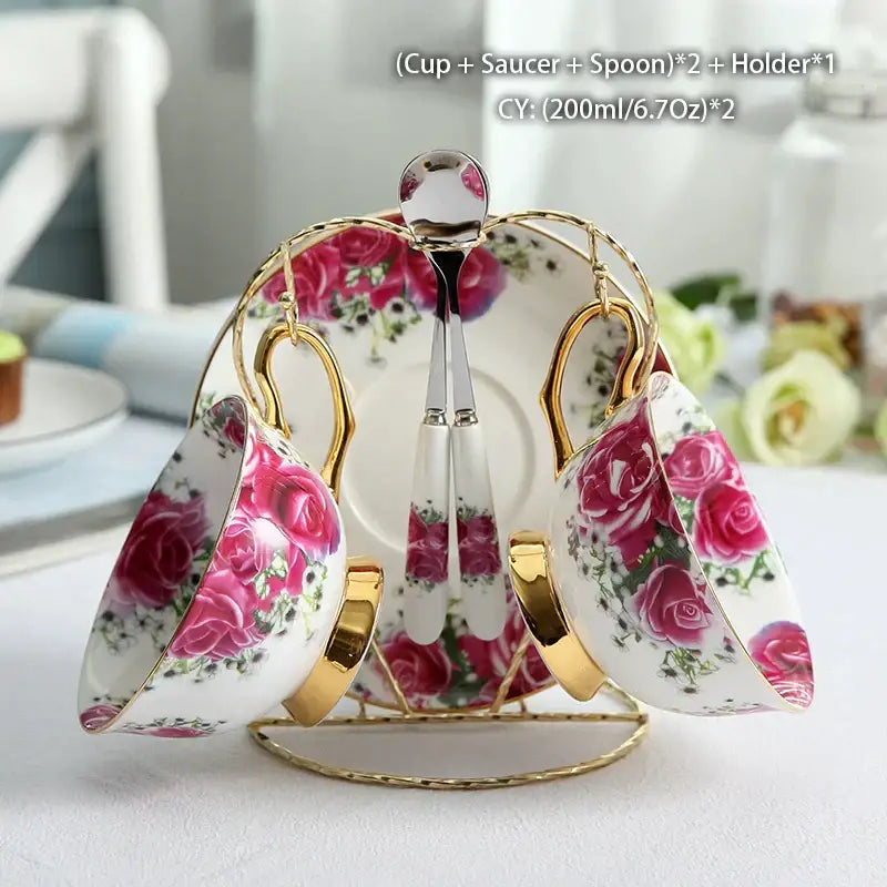 Elegant white bone china tea set with pink rose floral patterns and gold-trimmed handles in a gold metal stand by decorbites