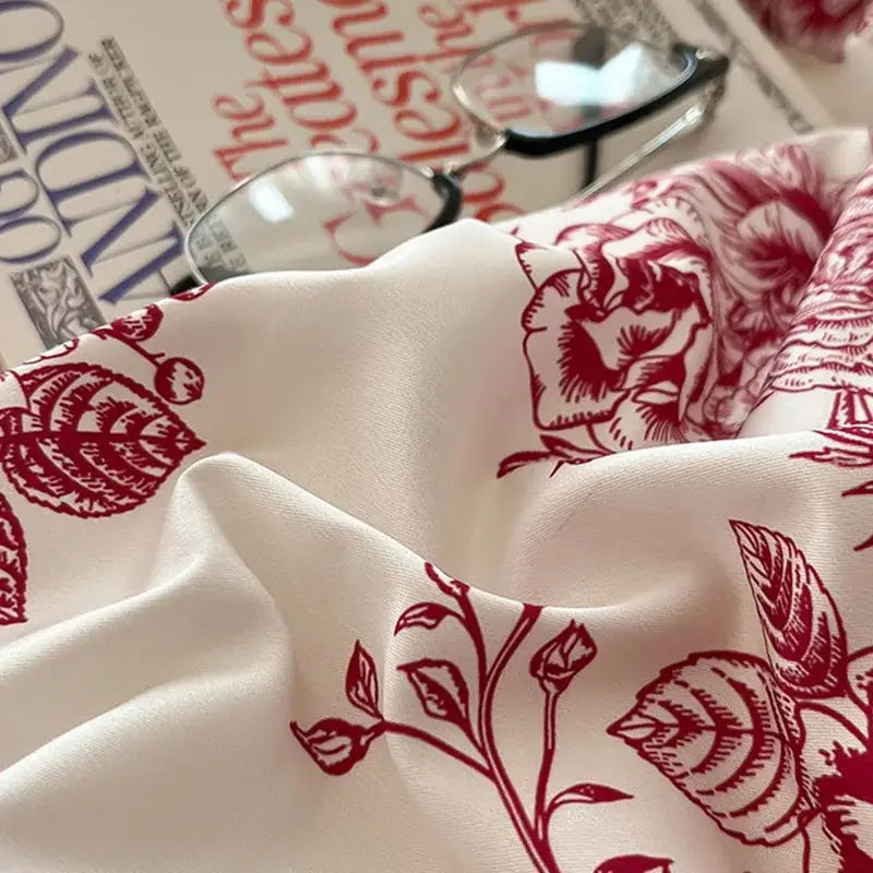 A soft off-white silk scarf with bold red rose floral pattern complementing decorbites cotton wide edge bedding sets