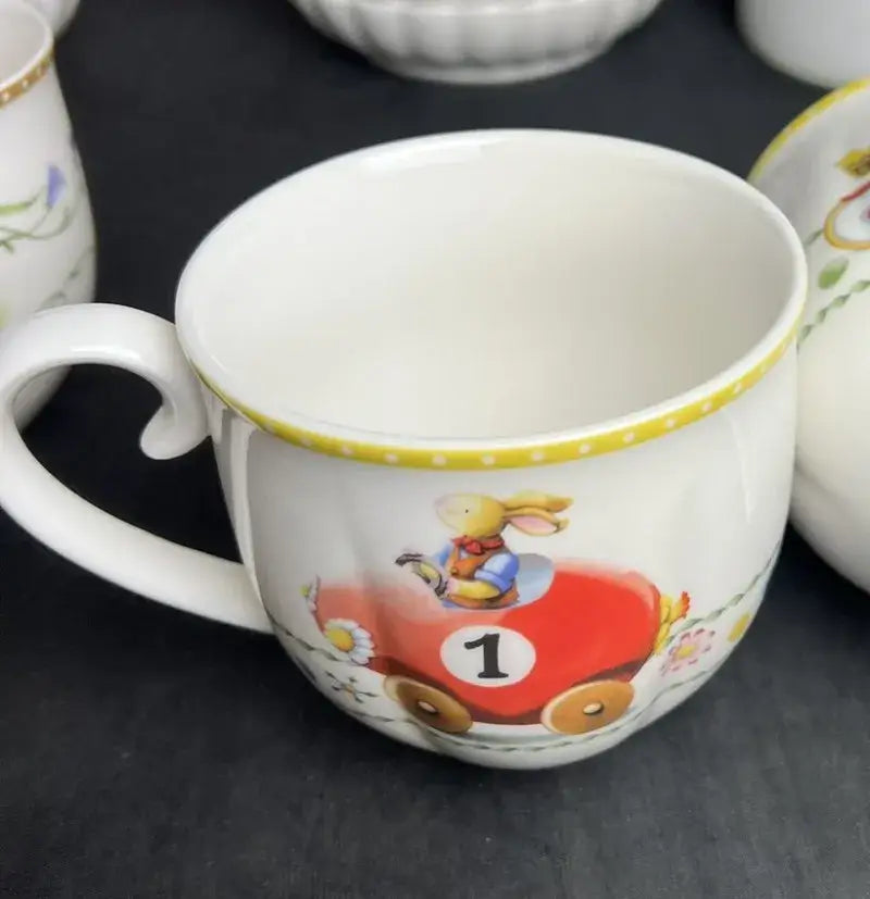 White ceramic mug with yellow polka-dotted rim and cartoon rabbit in red race car from floral scalloped tulip dinnerware set