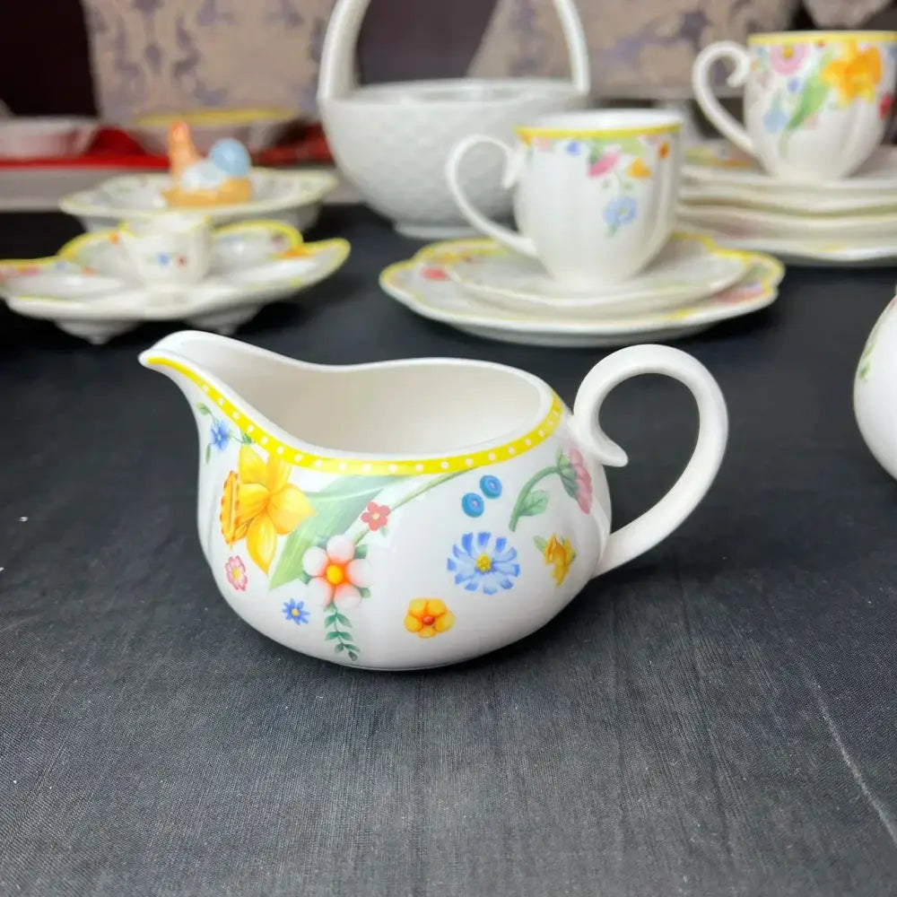 A white ceramic creamer with a vibrant floral pattern in the floral scalloped white porcelain tulip dinnerware set