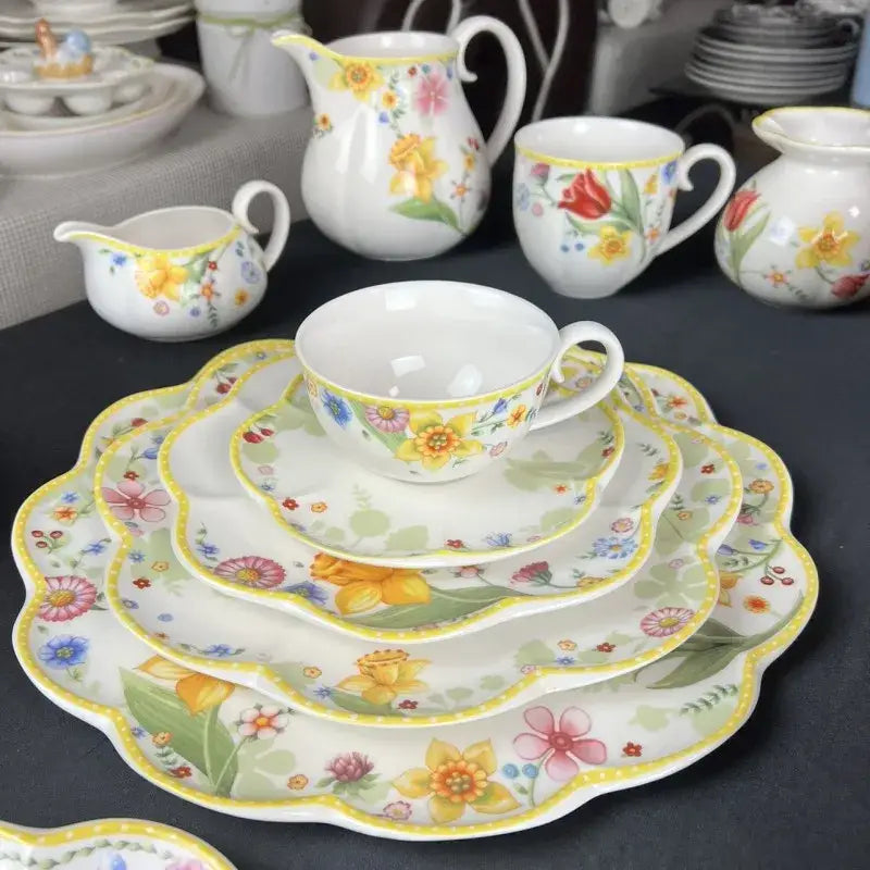 A delicate white ceramic teacup with a scalloped rim featuring vibrant yellow daffodils for a tulip dinnerware set