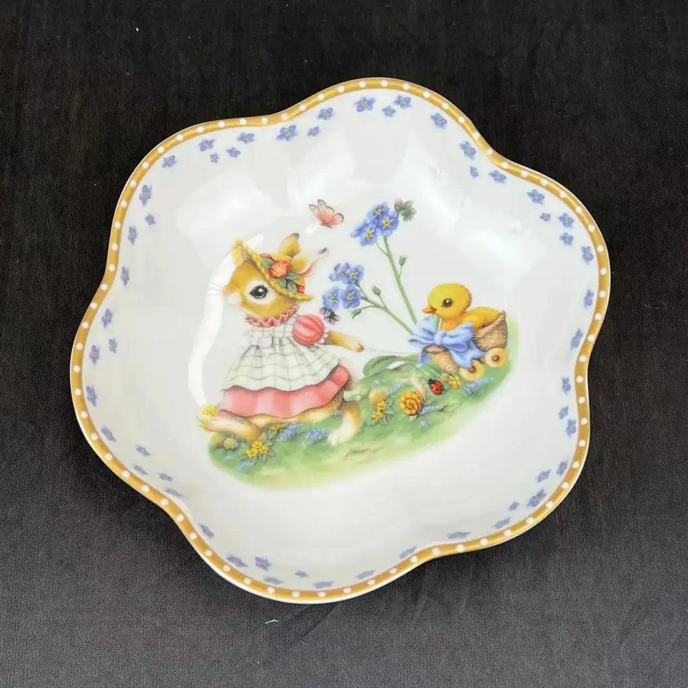 A delicate white porcelain scalloped dish featuring a bunny and chick illustration in a floral easter tulip dinnerware set