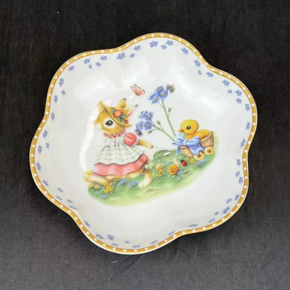A delicate white porcelain scalloped dish featuring a bunny and chick illustration in a floral easter tulip dinnerware set