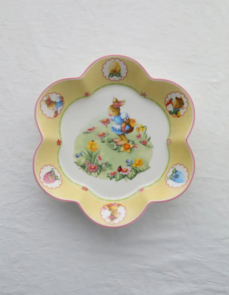 A delicate yellow ceramic bowl with scalloped edge and bunny illustration from floral scalloped white porcelain tulip dinnerware set