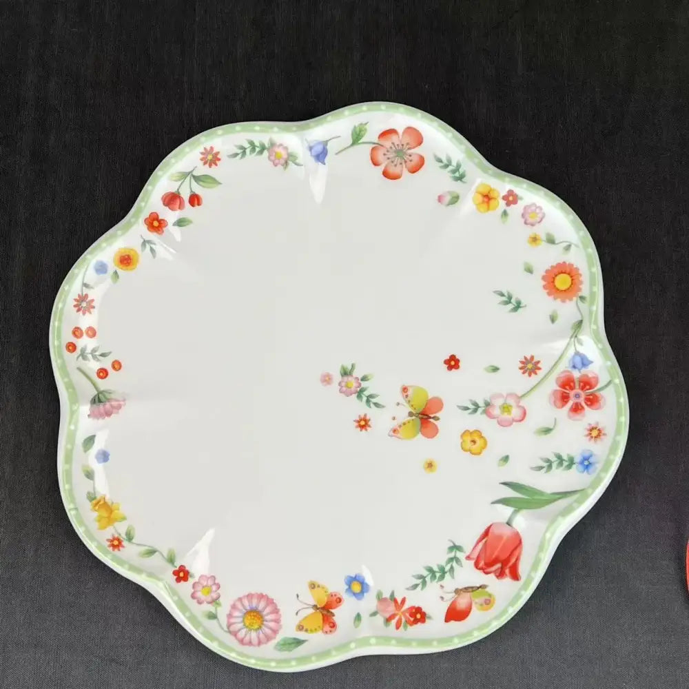 White ceramic scalloped plate with colorful floral and butterfly patterns in a tulip dinnerware set for dining room