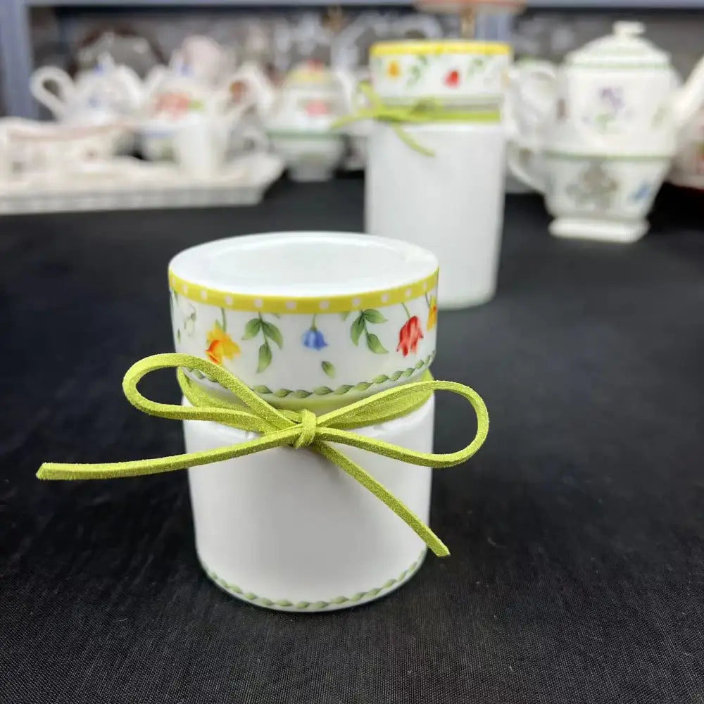 White ceramic egg cup with yellow rim and floral pattern tied with lime green ribbon in tulip dinnerware set
