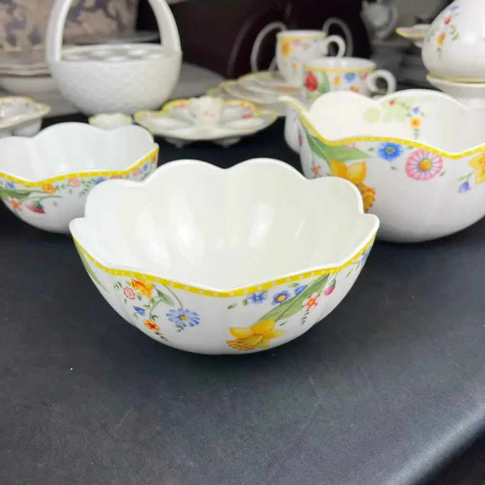 A white porcelain scalloped bowl with colorful floral patterns and a yellow border in a tulip dinnerware set